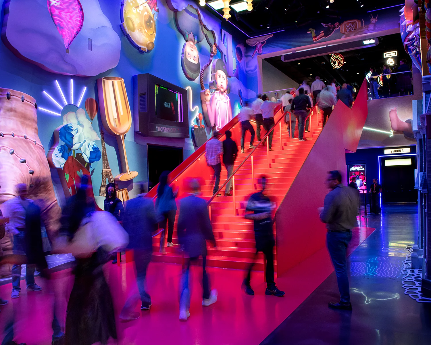People entering Netflix House and climbing the red staircase.