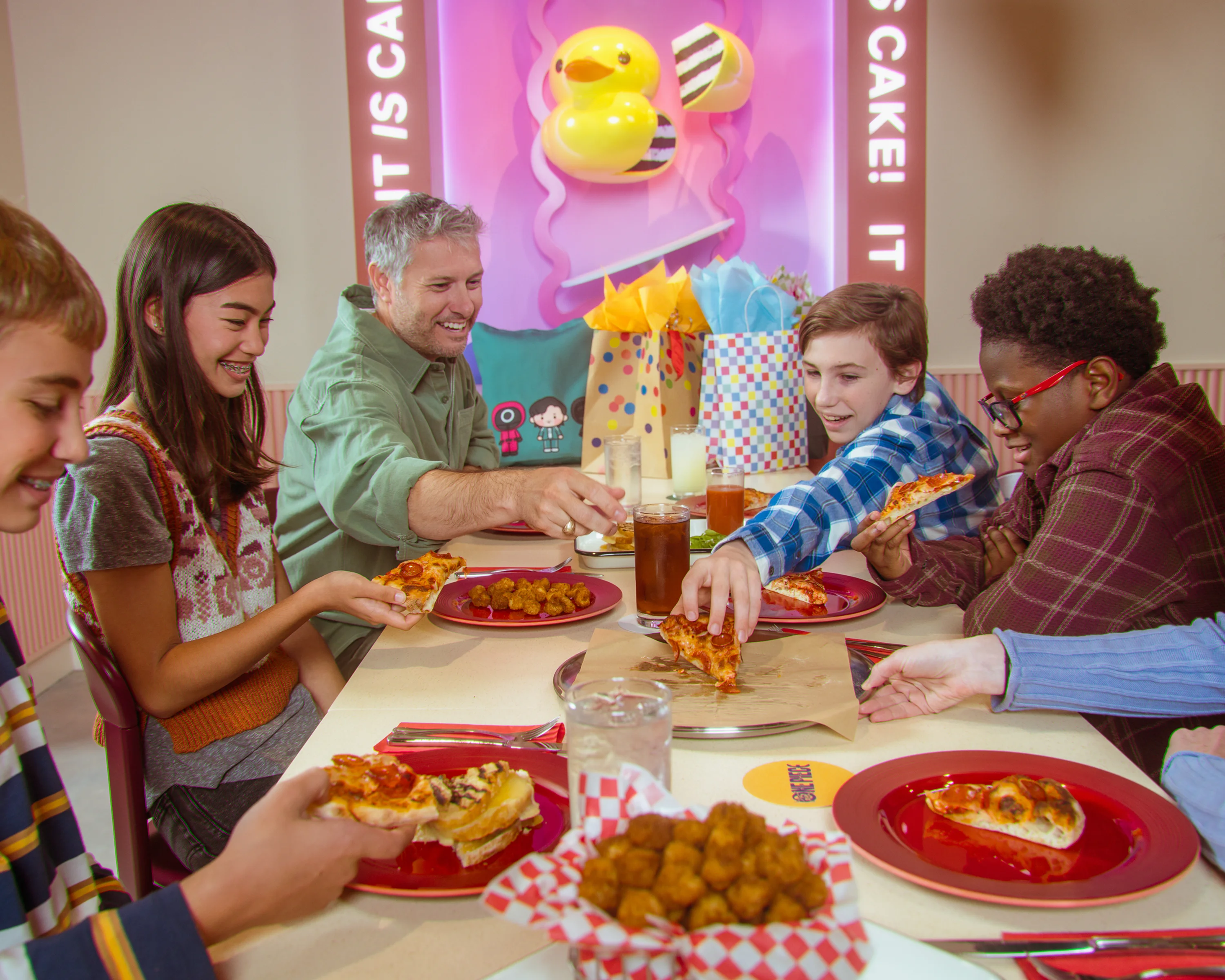 A group of 5 children and parent enjoy pizza and drinks for a birthday party at Netflix Bites.